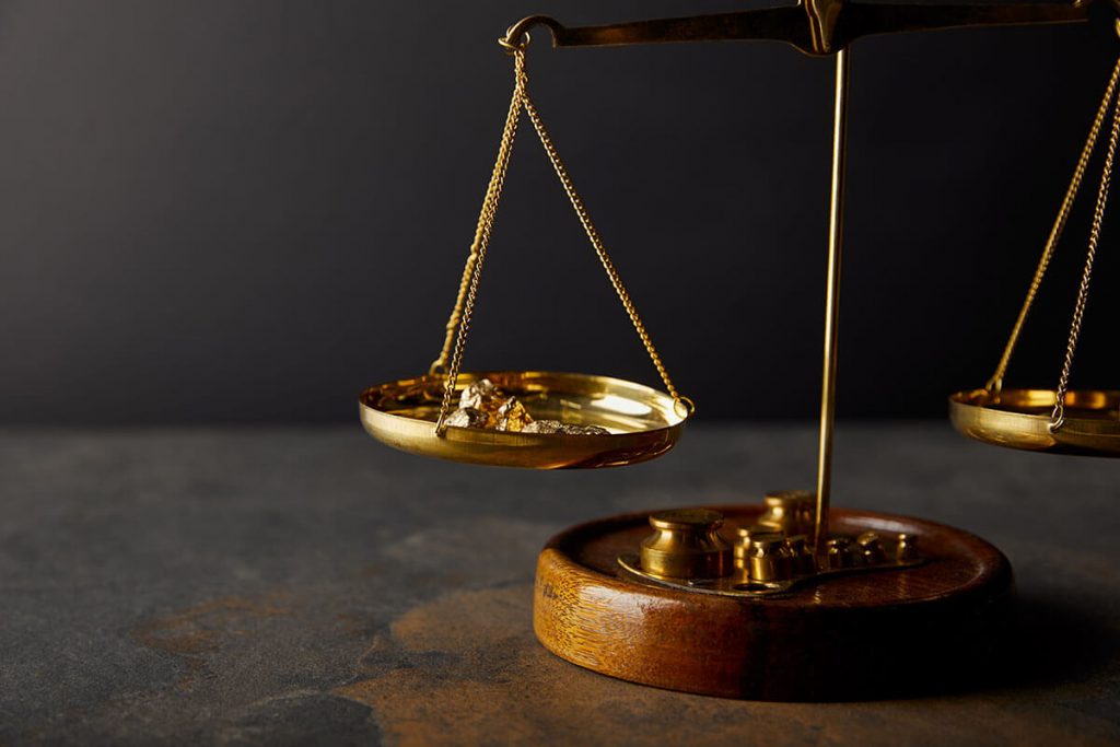 Goldene Waagschalen mit Gold-Nuggets auf einer Seite.